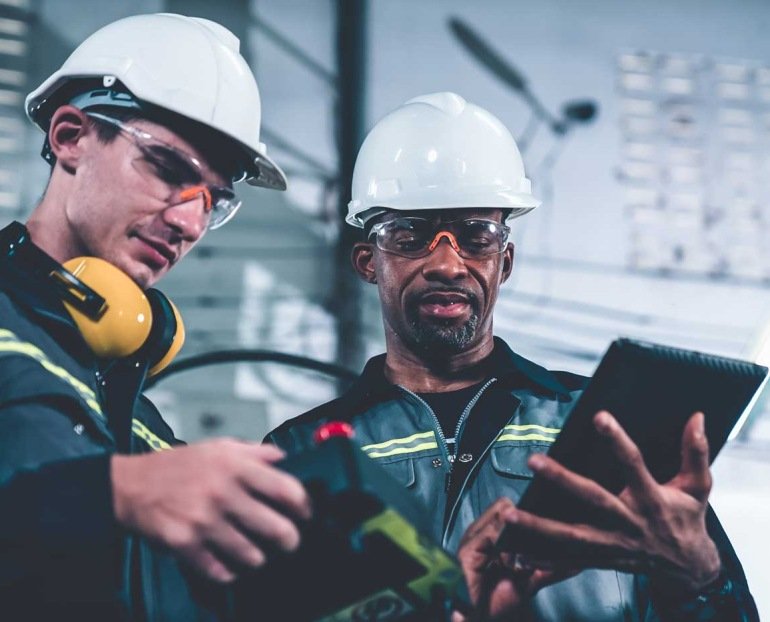 Two workers in a hard hat using a tablet